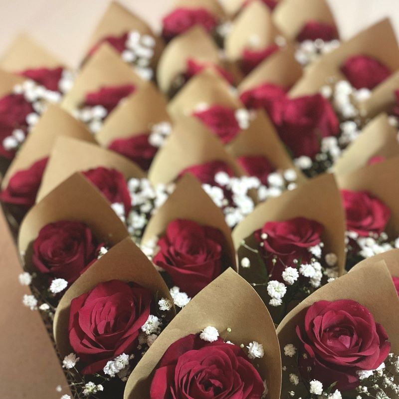 Bulk order of single-stalk red rose bouquets, accompanied by fresh white baby's breath, wrapped in rustic brown kraft paper 