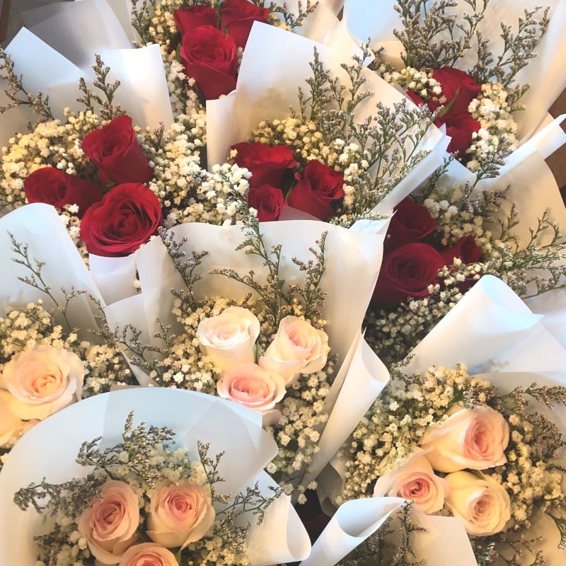 Bulk order of fresh 3-stalk red and pink rose bouquets, accompanied by fresh white baby's breath, wrapped in matte white wrapping paper 