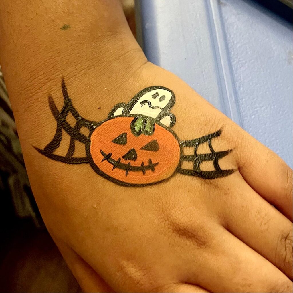 Facepainting for Children's parties by The Kindled Collective - halloween design pumpkin on hand