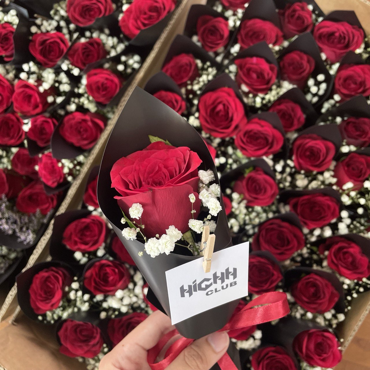 Bulk order of single-stalk red rose bouquets, accompanied by fresh white baby's breath, wrapped in matte black wrapping paper 