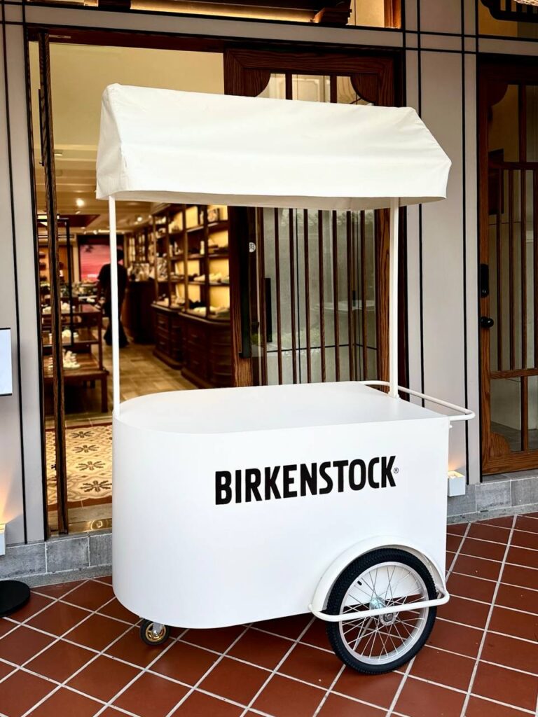 Off-white mobile pushcart with canopy roof, comes with large storage compartment. Fully customisable from cart body wrapping, simple logo customisation to printing of logo on the cart roof. Our pushcart is available in both black and off white. Perfect for reception tables, product displays, coffee cart, flower bars, or as a centerpiece to any event.
