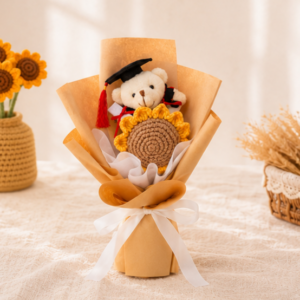 A graduation bouquet featuring a handcrafted crochet sunflower and mini graduation bear! A sweet keepsake that's perfect for celebrating their special day. A single-stalk crochet sunflower wrapped in brown kraft paper and white ribbon. Topped with a graduation bear in either brown or white!